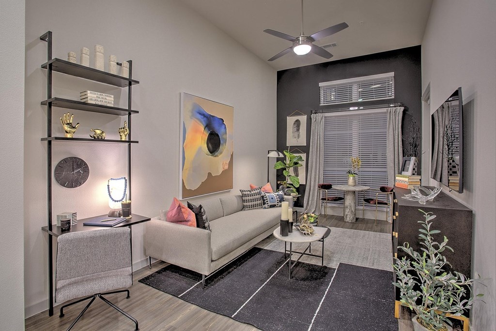 A living room with a white couch, a black shelf, and a painting on the wall.
