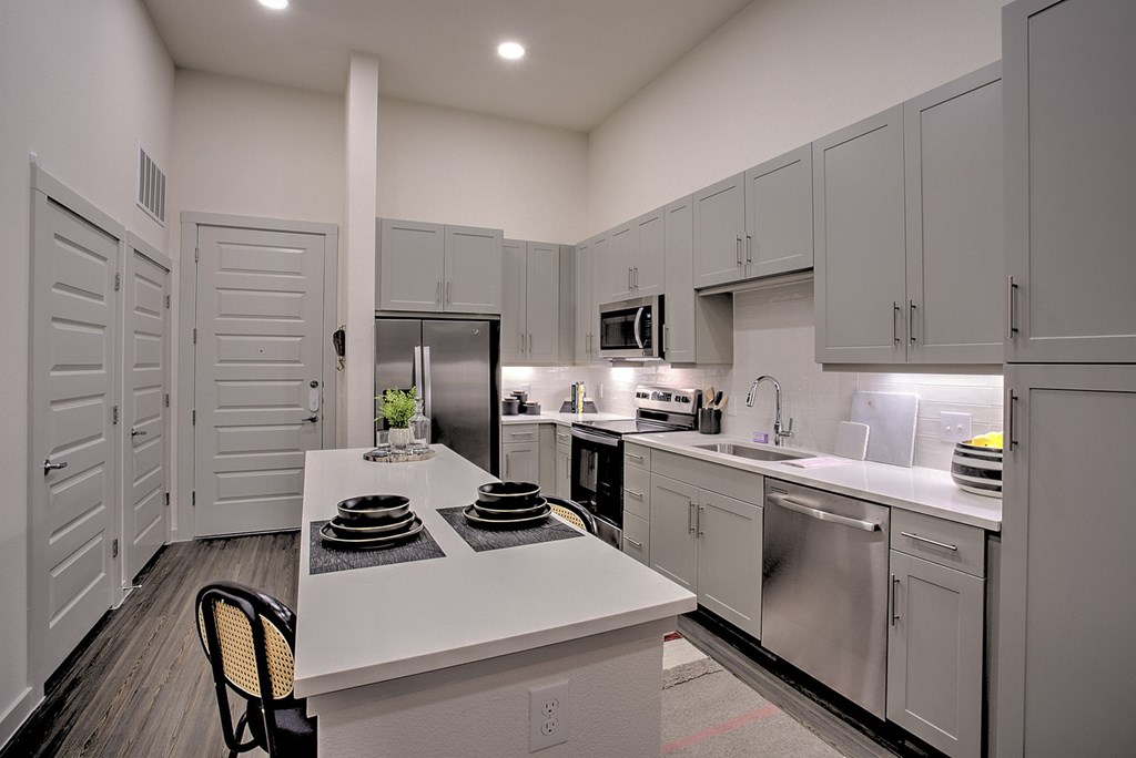 A kitchen with white cabinets and a white island with plates on it.