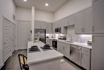 A kitchen with white cabinets and a white island with plates on it.
