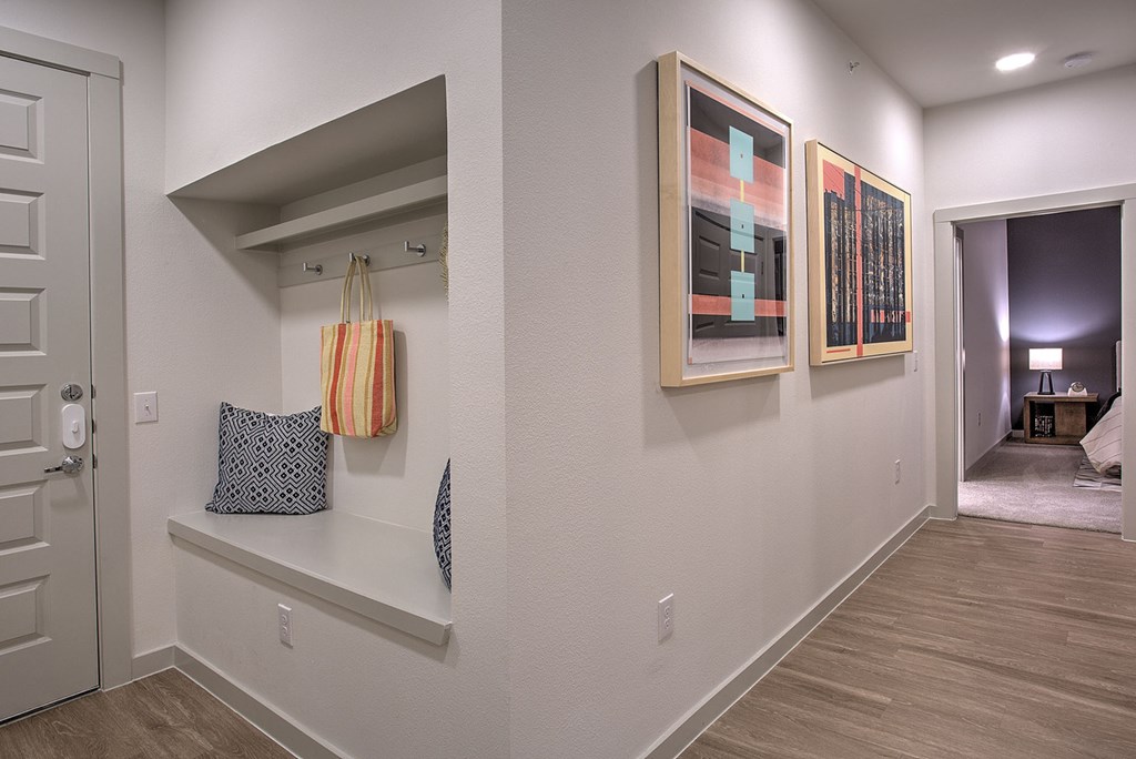 A hallway with a bench and two paintings on the wall.
