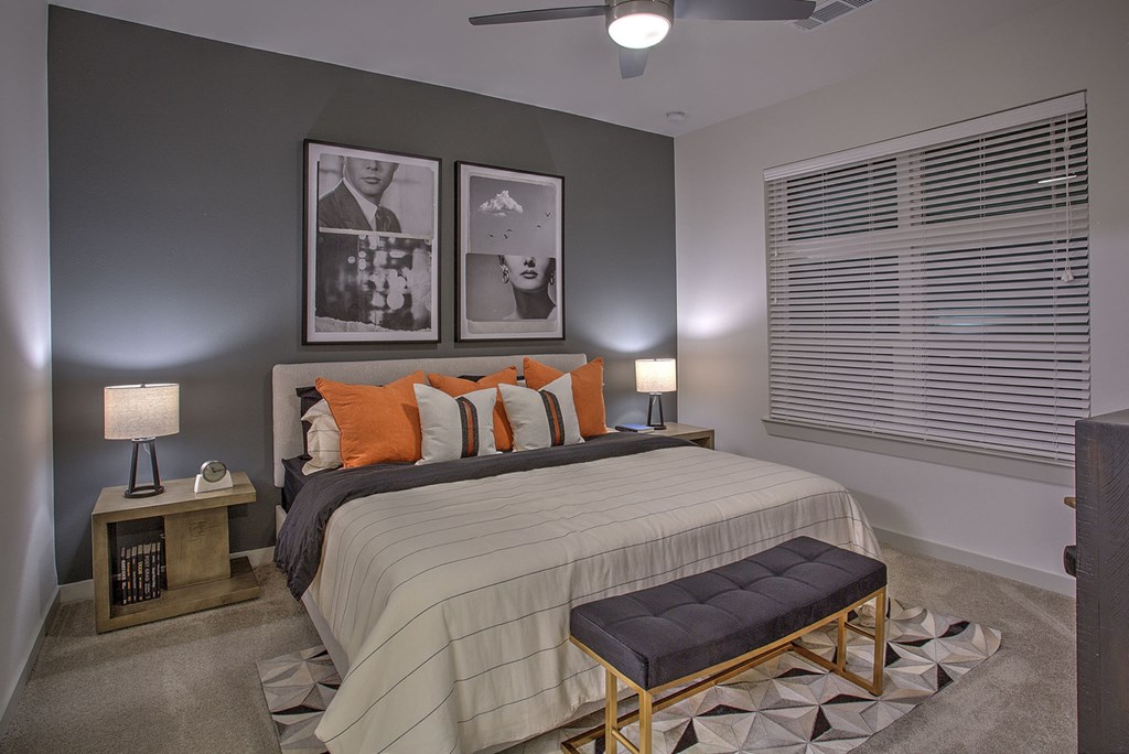 A bedroom with a bed, two lamps, and pictures on the wall.