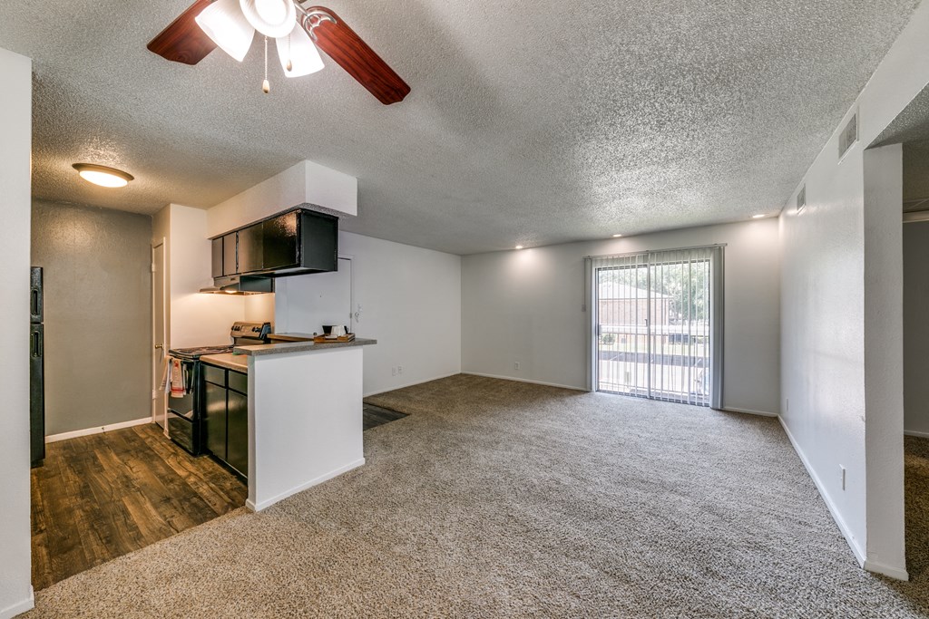 an empty living room and kitchen with a door to a balcony