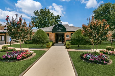 an exterior view of a brick building with a green awning and landscaping
