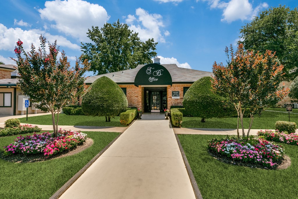 an exterior view of a brick building with a green awning and landscaping