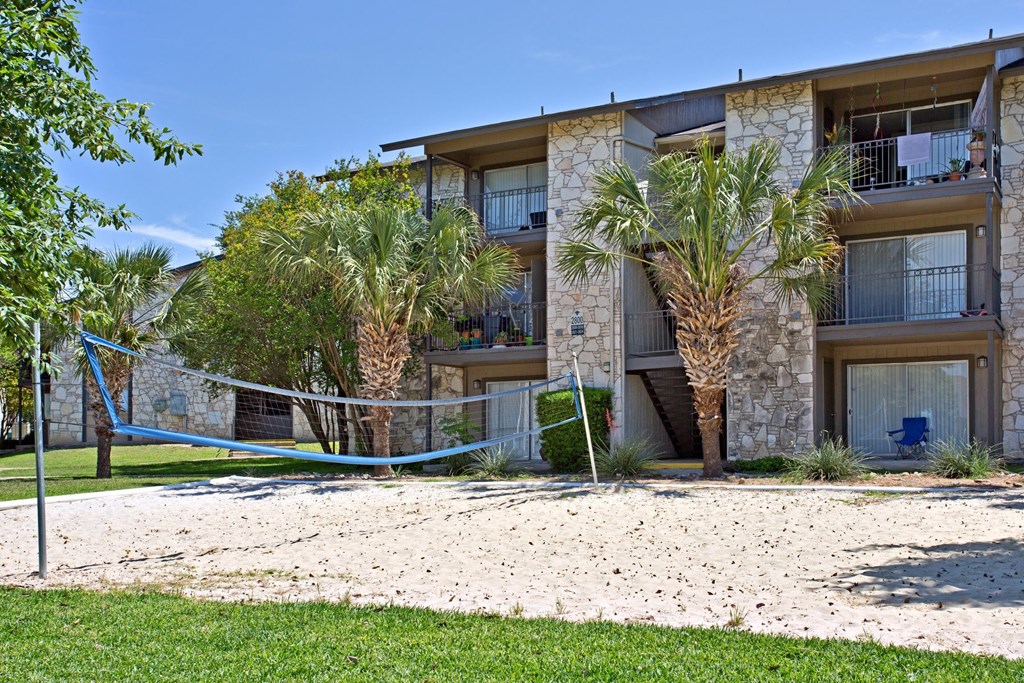 an apartment building with a sandy beach and palm trees