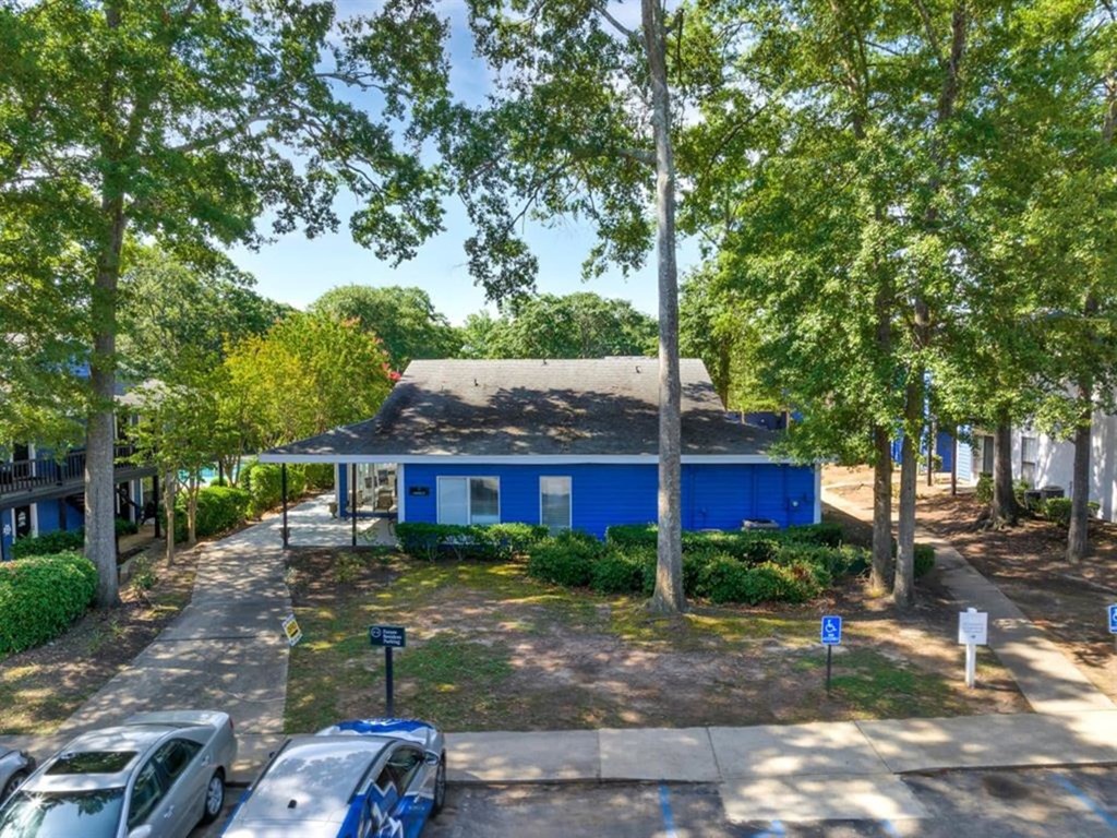 an aerial view of a blue house with a parking lot and trees