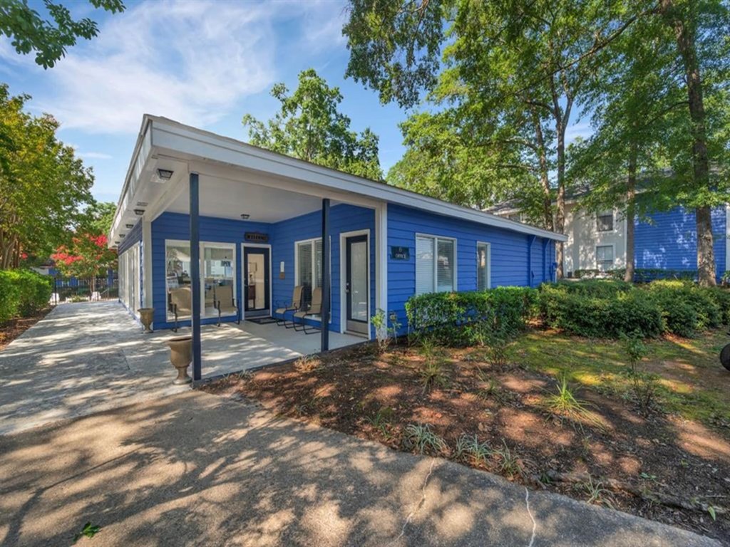 a blue house with a sidewalk and trees in front of it