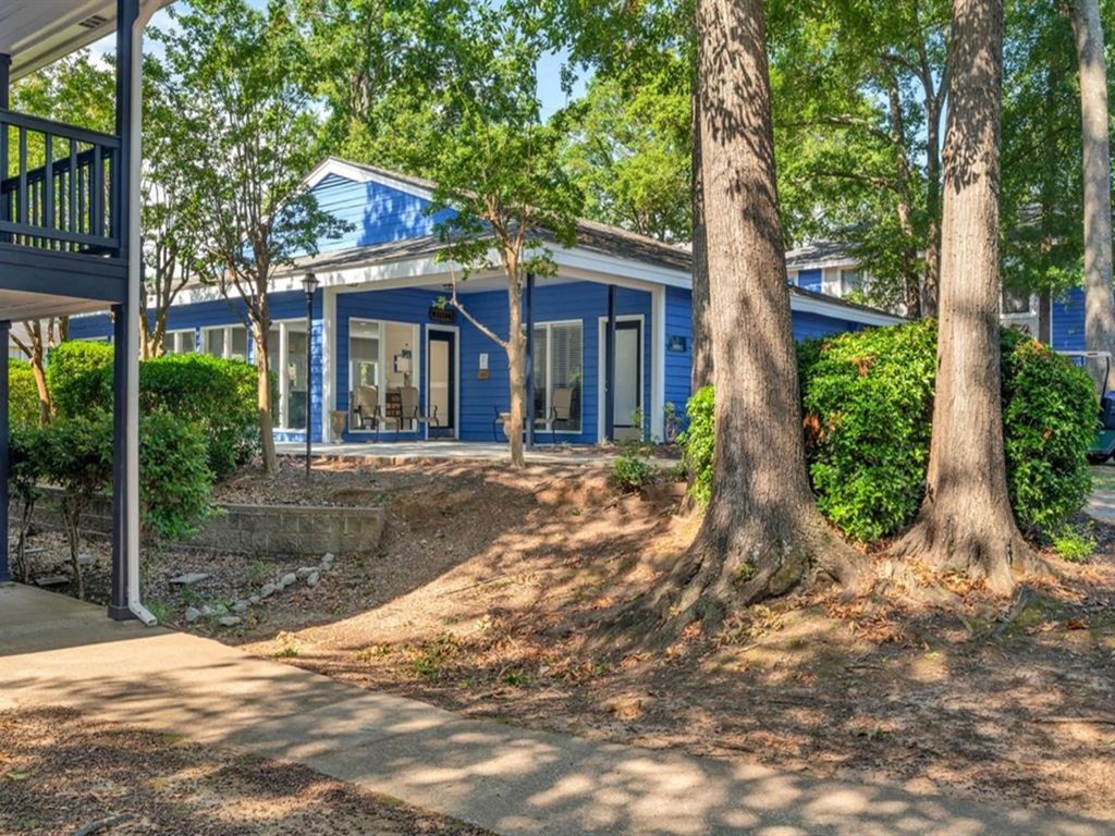 a blue house with trees and a sidewalk in front of it