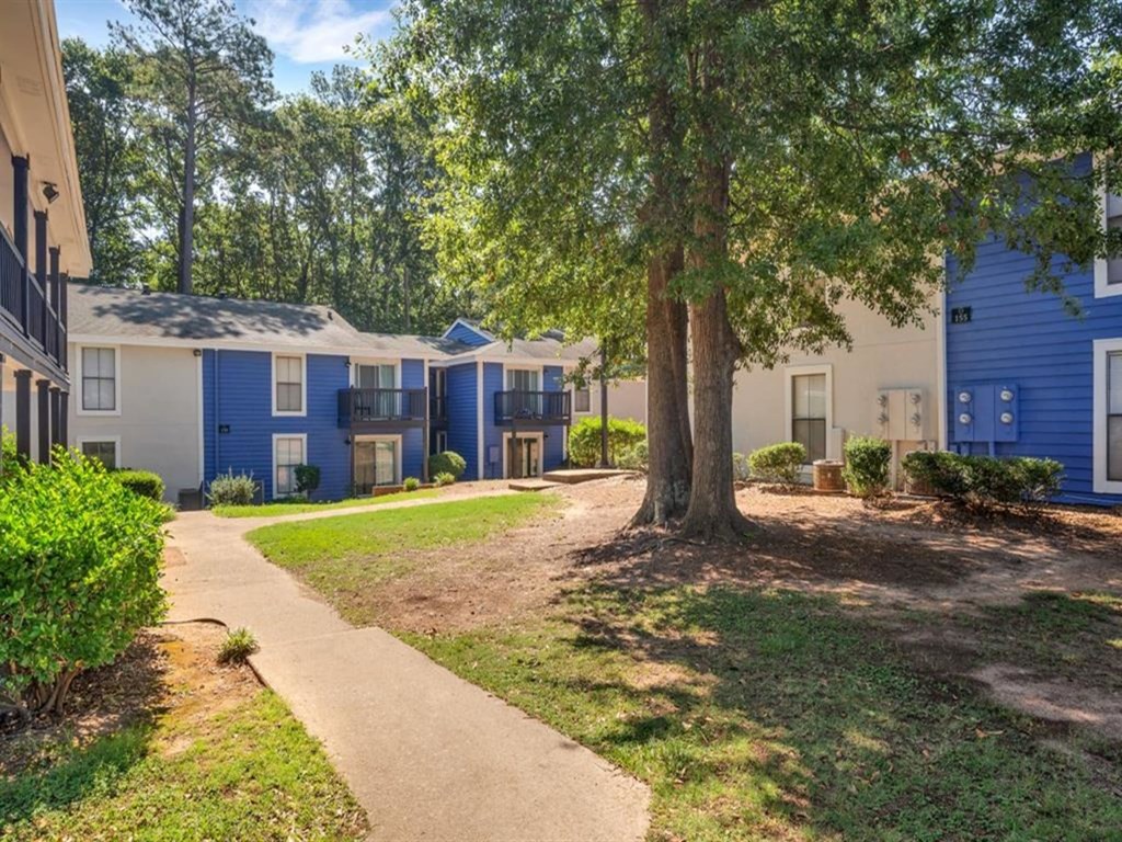 a pathway between several blue and white houses with trees