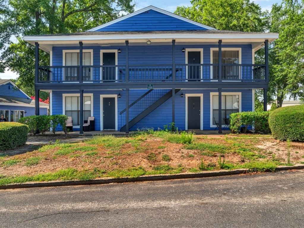 a blue house with a porch and a street in front of it