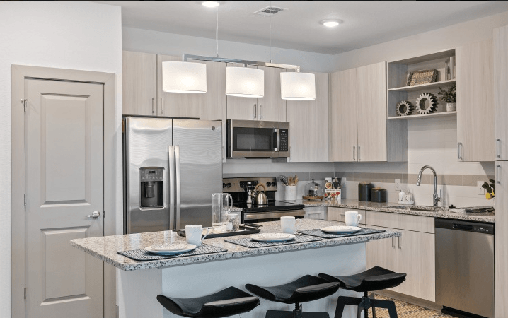 A modern kitchen with a granite countertop and stainless steel appliances.