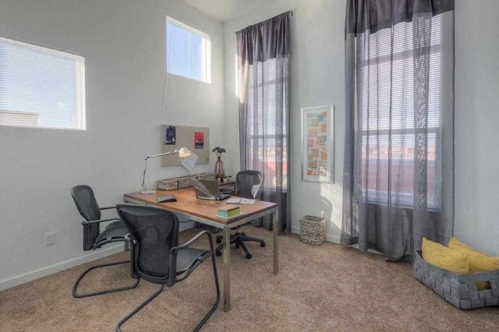 a home office with a desk and two windows