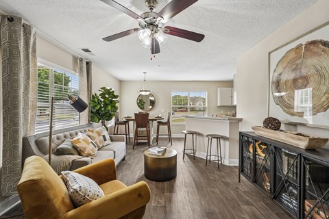 A living room with a yellow chair and a ceiling fan.