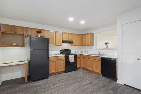 A kitchen with a black refrigerator and wooden cabinets.