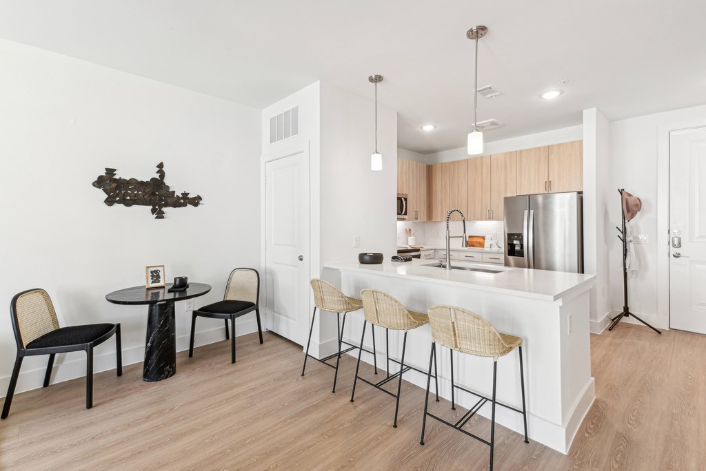 A kitchen with a white counter and black chairs.