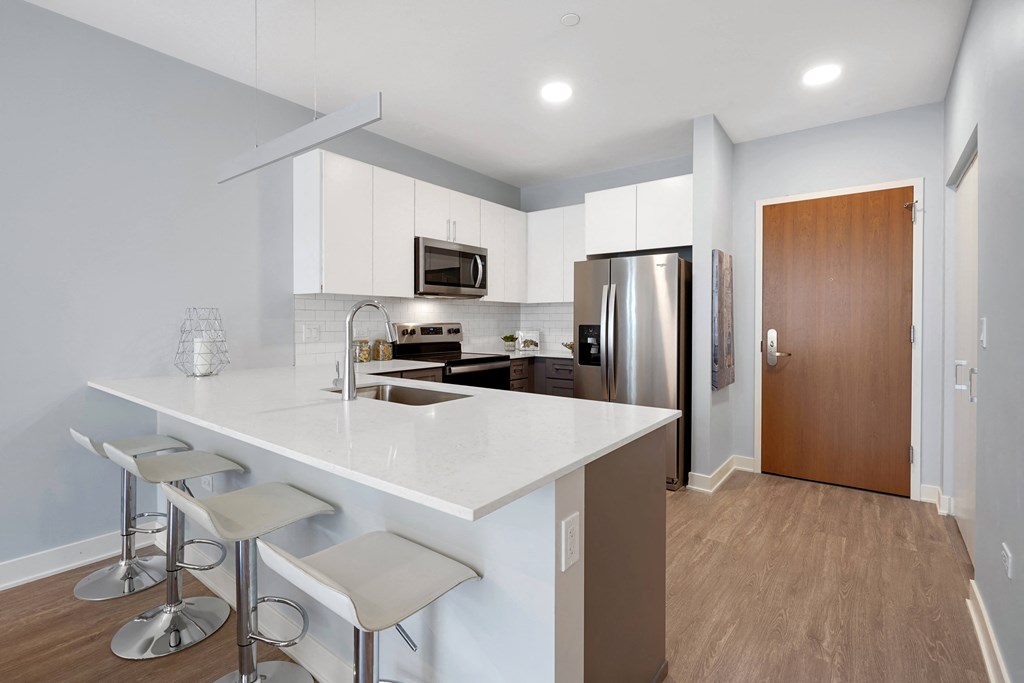 a kitchen with white cabinets and a large white island with three stools
