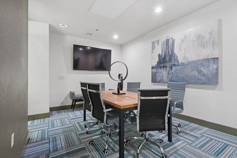 A conference room with a large painting on the wall and a television.
