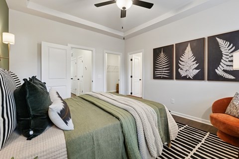 A bedroom with a bed, pillows, a blanket, a chair, and a ceiling fan.