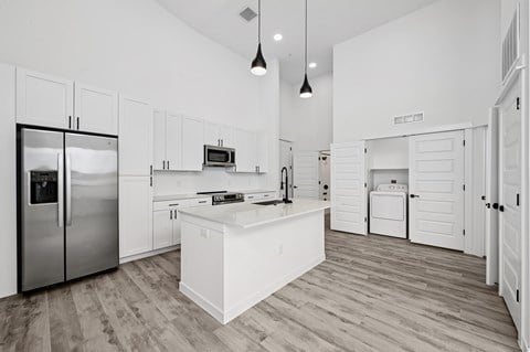 A modern kitchen with a refrigerator, microwave, oven, and cabinets.