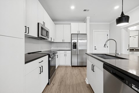 A modern kitchen with white cabinets and stainless steel appliances.