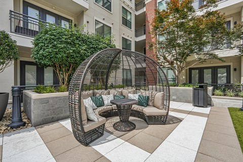A patio with a wicker table and chairs.