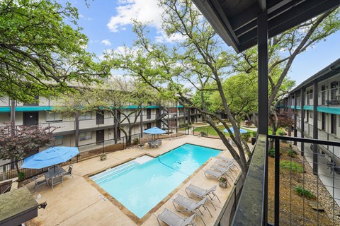 A pool surrounded by trees and chairs.