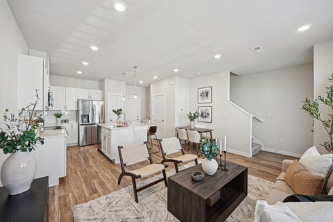 A modern living room with a wooden coffee table and a dining area in the background.