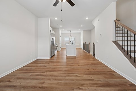 A long hallway with a ceiling fan and wooden floors.