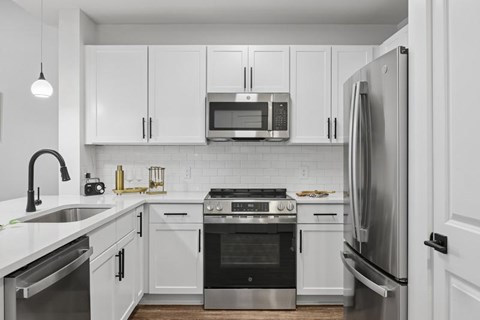 A modern kitchen with white cabinets and stainless steel appliances.
