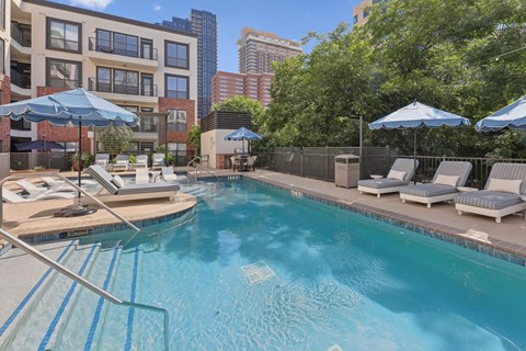A swimming pool with a metal ladder and sun loungers.