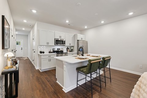 A modern kitchen with white cabinets and a wooden floor.