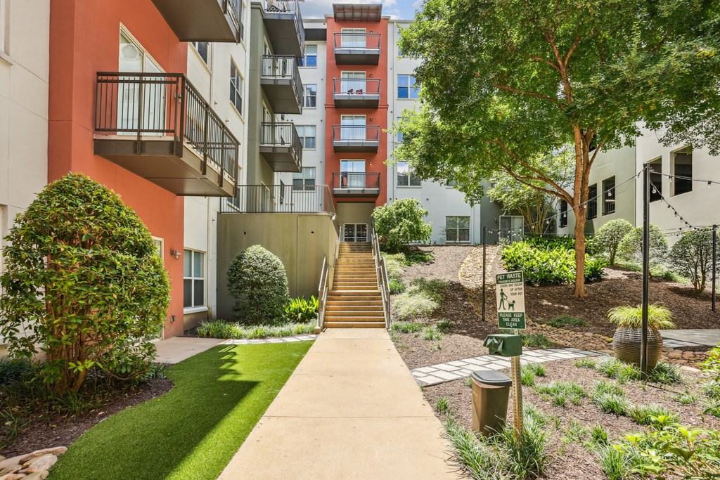 A pathway leads up a set of stairs in a landscaped courtyard.
