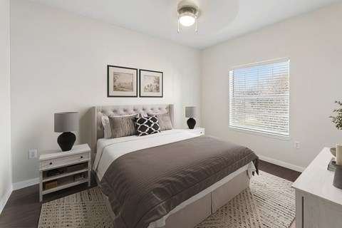A bedroom with a large bed and a nightstand with a lamp.