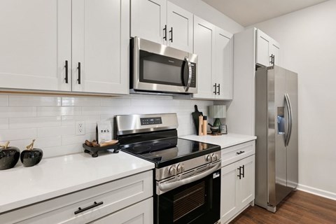 A modern kitchen with white cabinets and stainless steel appliances.