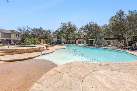 A large outdoor swimming pool surrounded by a stone patio.