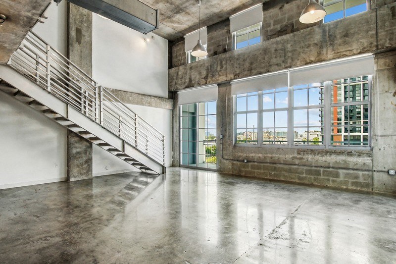 the living room has a large window and concrete floors and a staircase