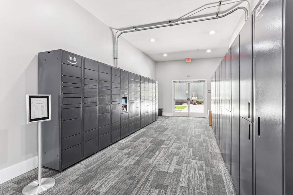 A hallway with a sign on a stand and a row of lockers on the wall.