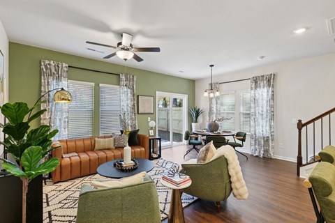 A living room with a brown leather couch, a green armchair, and a round table with a candle on it.