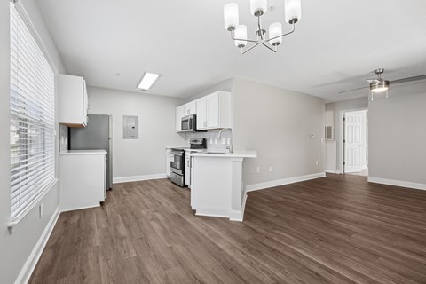 A kitchen with white cabinets and a wooden floor.
