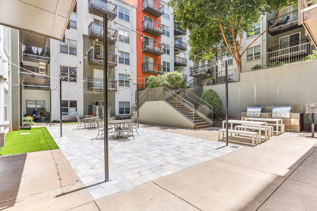 A patio area with a table and chairs is surrounded by apartment buildings.