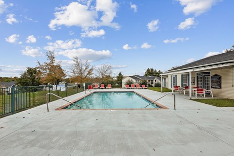 A swimming pool in a backyard with a fence and trees.