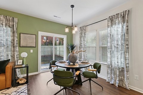 A dining room with a table set for four and a view of a backyard.