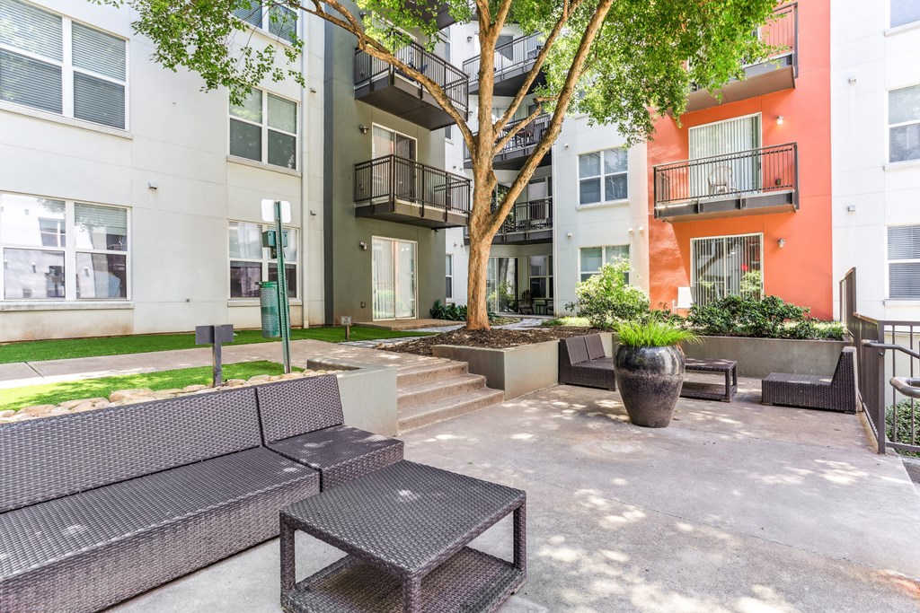 A patio with a couch, table, and potted plants.