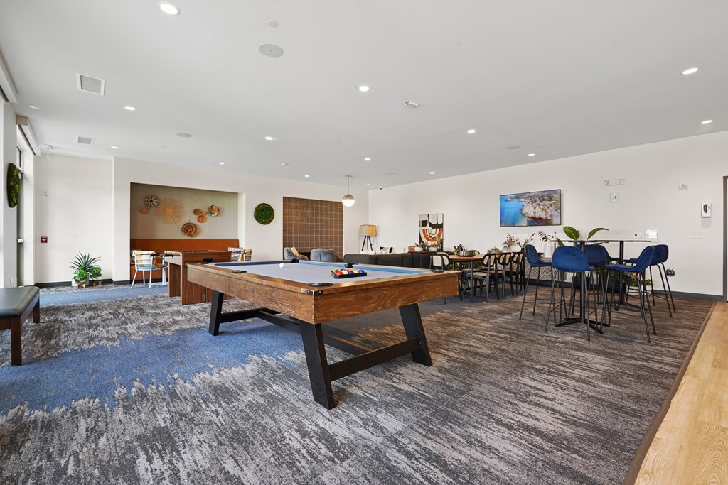 a spacious room with a pool table in the center of it and tables and chairs in the