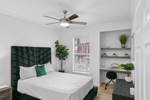 A bedroom with a bed, desk, and chair.