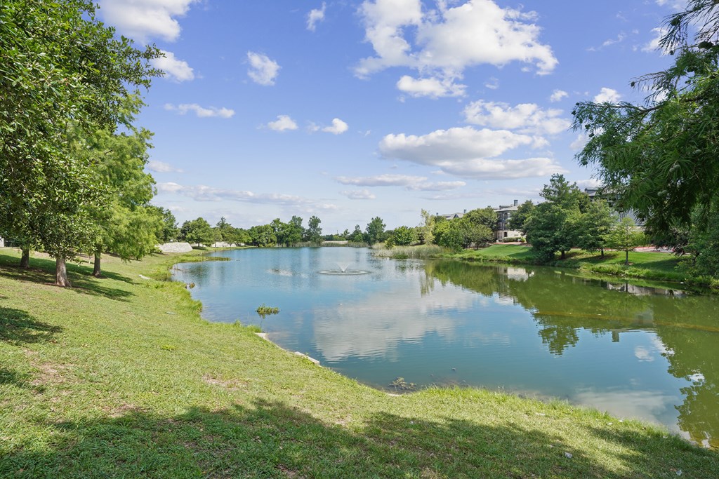 A serene lake surrounded by lush greenery under a clear blue sky.