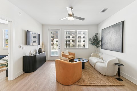 A living room with a brown rug and a ceiling fan.