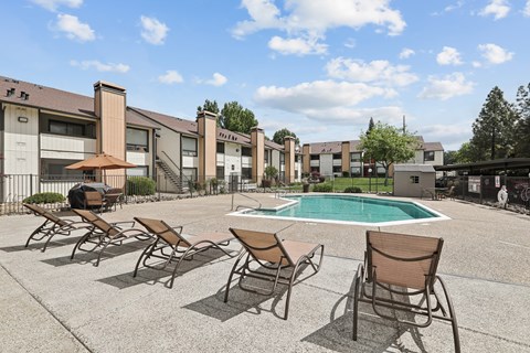 A pool surrounded by chairs and buildings.