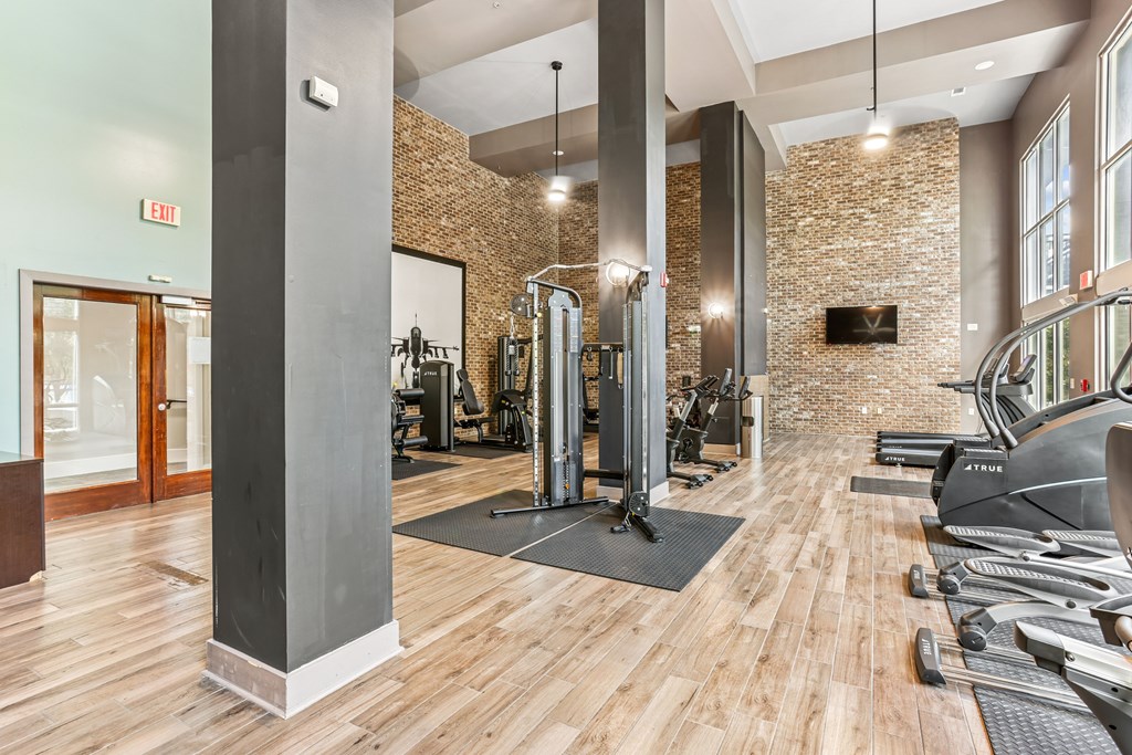 A gym with a variety of equipment and a brick wall.
