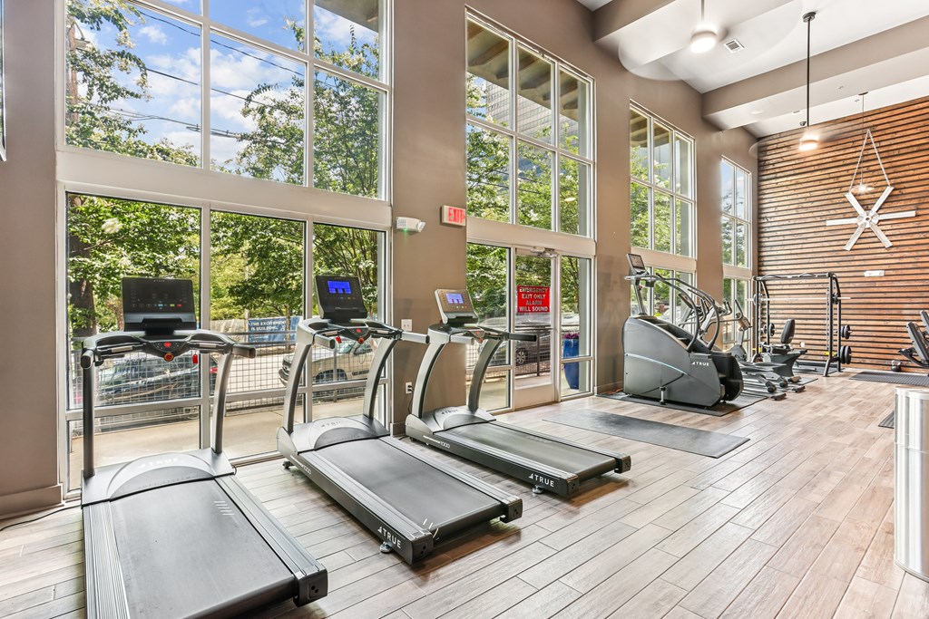 A gym with treadmills and a wooden floor.